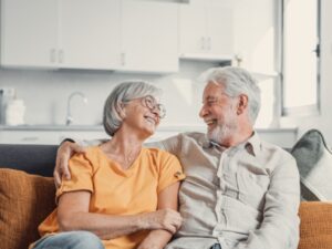 Happy laughing older married couple talking, laughing, standing in home interior together, hugging with love, enjoying close relationships, trust, support, care, feeling joy, tenderness